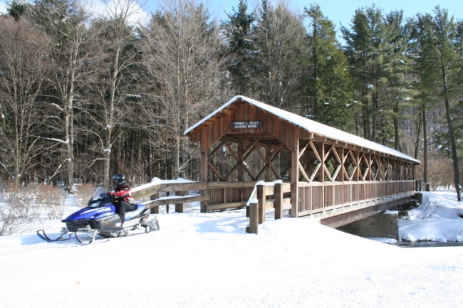 Snowmobiler exiting the Thomas Kelly Covered Bridge at Allegany State Park