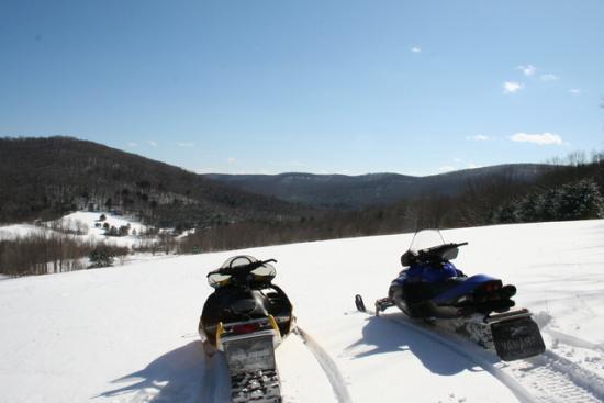 Two snowmobiles in the foreground with a Great View of the hillsides